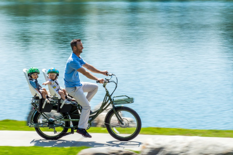 Man riding a Pedego Stretch electric bike with two kids as passengers