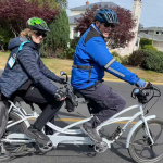 A couple rides their white Pedego tandem electric bike.