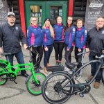 Pedego store owners with two bikes donated to a cycling team for raffle.