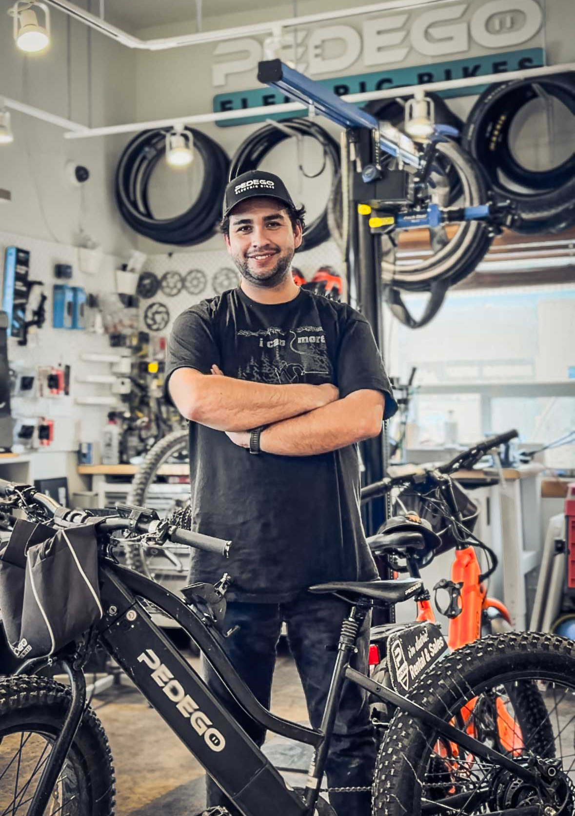 Shop lead at Pedego Canmore store stands in mechanic space with Pedego ebike.