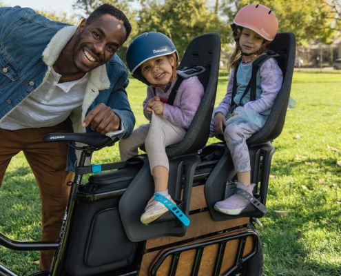 Adult loading two children on their Pedego Cargo Ebike. How to Safely Cruise with Kids on Your Pedego EBikes